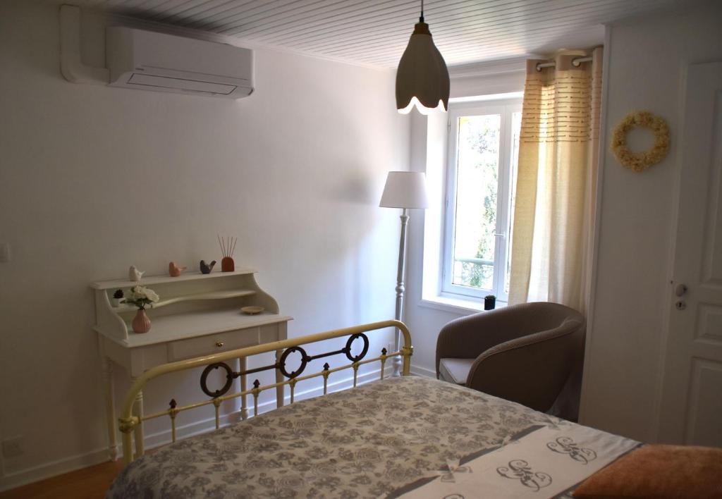 a bedroom with a bed and a chair and a window at Gîte NAO in Serves-sur-Rhône