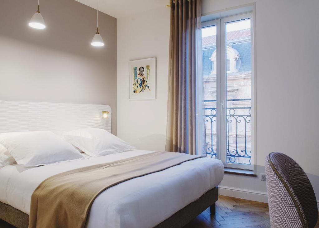 a bedroom with a large bed and a window at Hôtel le XIX in Béziers