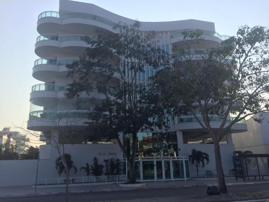 um edifício alto com árvores em frente em Apto Bella Aurora em Cabo Frio