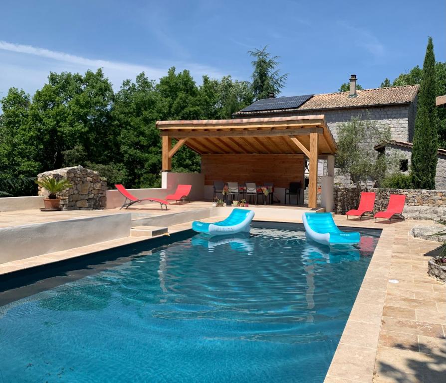 a swimming pool with chairs and a pavilion at Chambre d'hôtes avec climatisation, terrasse privée et accès piscine in Saint Alban Auriolles