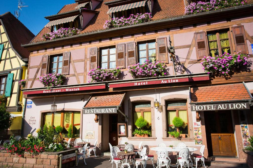 a building with tables and chairs in front of it at Hôtel Au Lion in Ribeauvillé