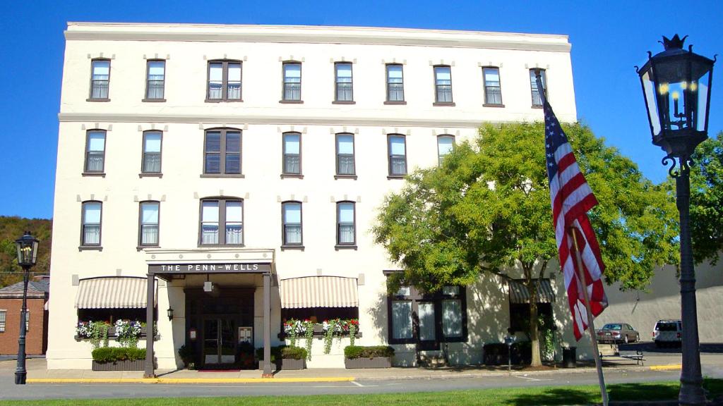 un bâtiment blanc arborant un drapeau américain devant lui dans l'établissement Penn Wells Hotel, à Wellsboro