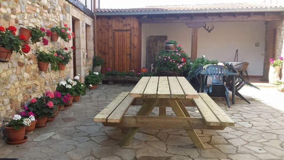 a wooden picnic table on a patio with flowers at Casa Rural Valle Tosande in Cantoral