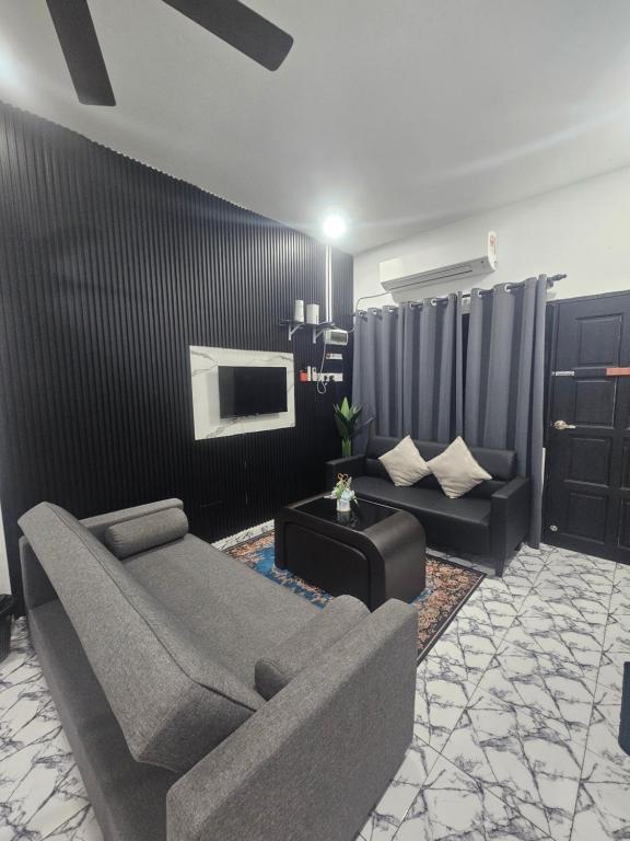 a living room with a couch and a tv at Homestay Una Kangar in Kangar