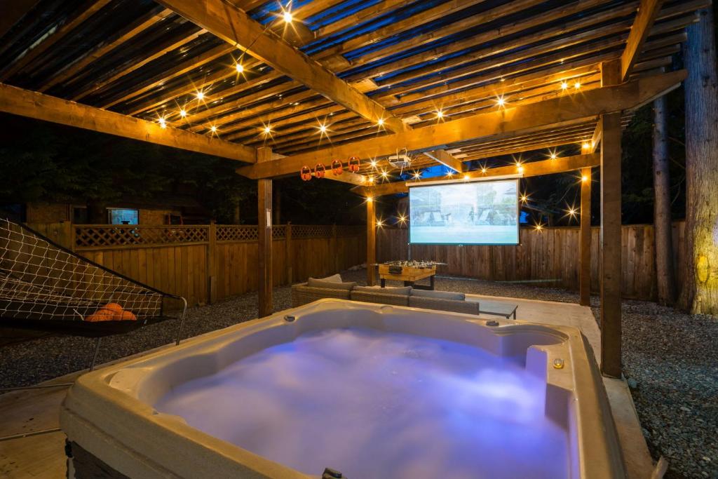 a large bath tub in a backyard with a tv at Bunny Bliss - Upper Level HotTub FirePit Theatre in Langley