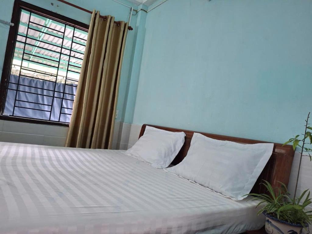 a bedroom with a bed with white sheets and a window at Tam hien ho in Tân Hiệp