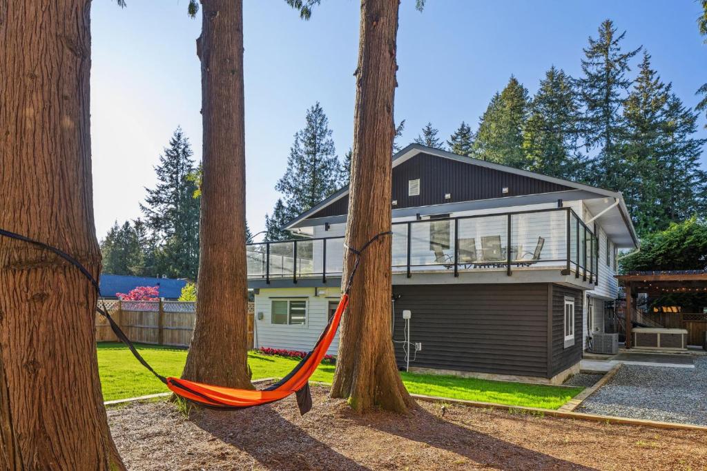 a hammock between two trees in front of a house at Bunny Bliss - Lower Level HotTub FirePit Theatre in Langley