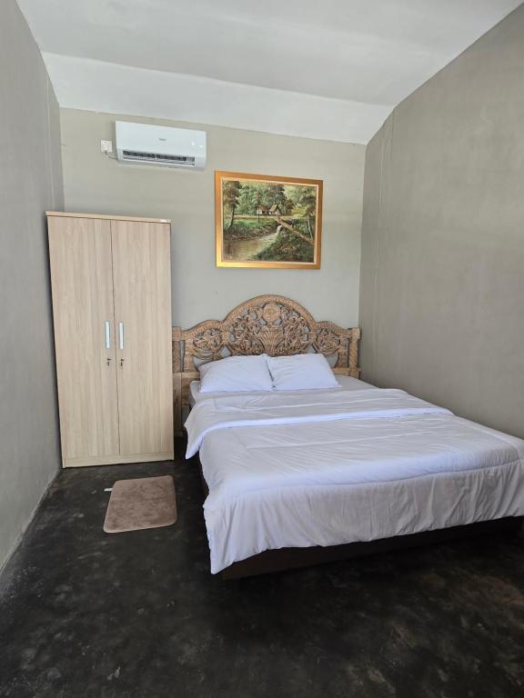 a bedroom with a large bed and a cabinet at Homestay IDR Bali in Jimbaran