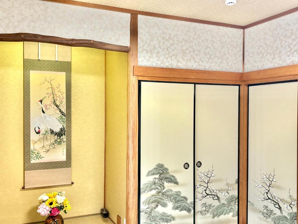 a room with glass doors and paintings on the wall at 明月民宿 in Takatsuki