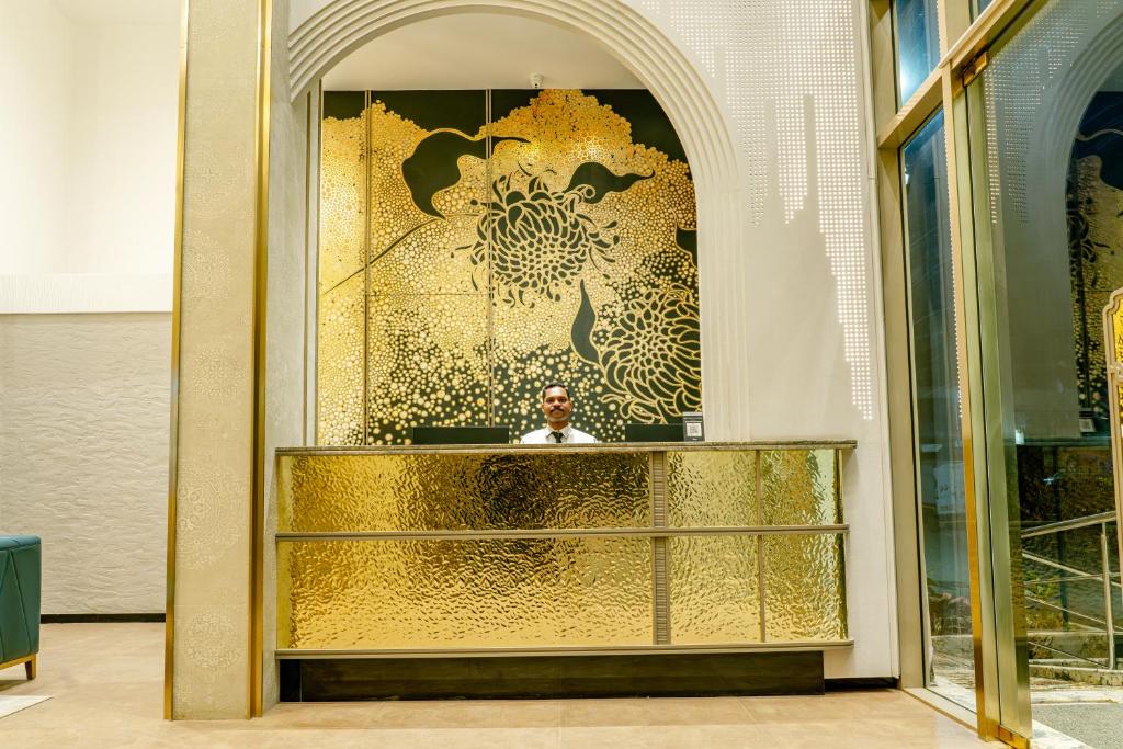a man sitting at a desk in a gold lobby at SVS Bhawan in Ulhāsnagar