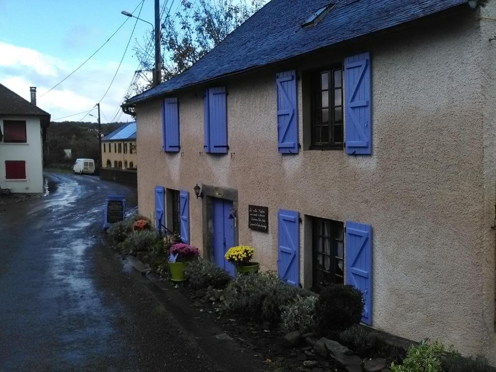 una casa con puertas azules y flores delante de ella en Maison d'hôtes et Campement Mariposa, en Lanne