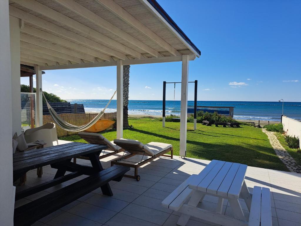 a patio with a hammock and a view of the ocean at Ammos Beachfront Villa Paradise in Larnaca