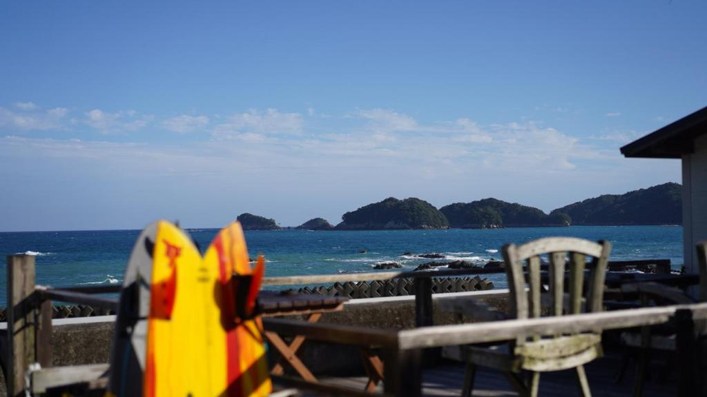 a view of the ocean from a deck with a table and chairs at PavilionSurf&Lodge in Shishikui