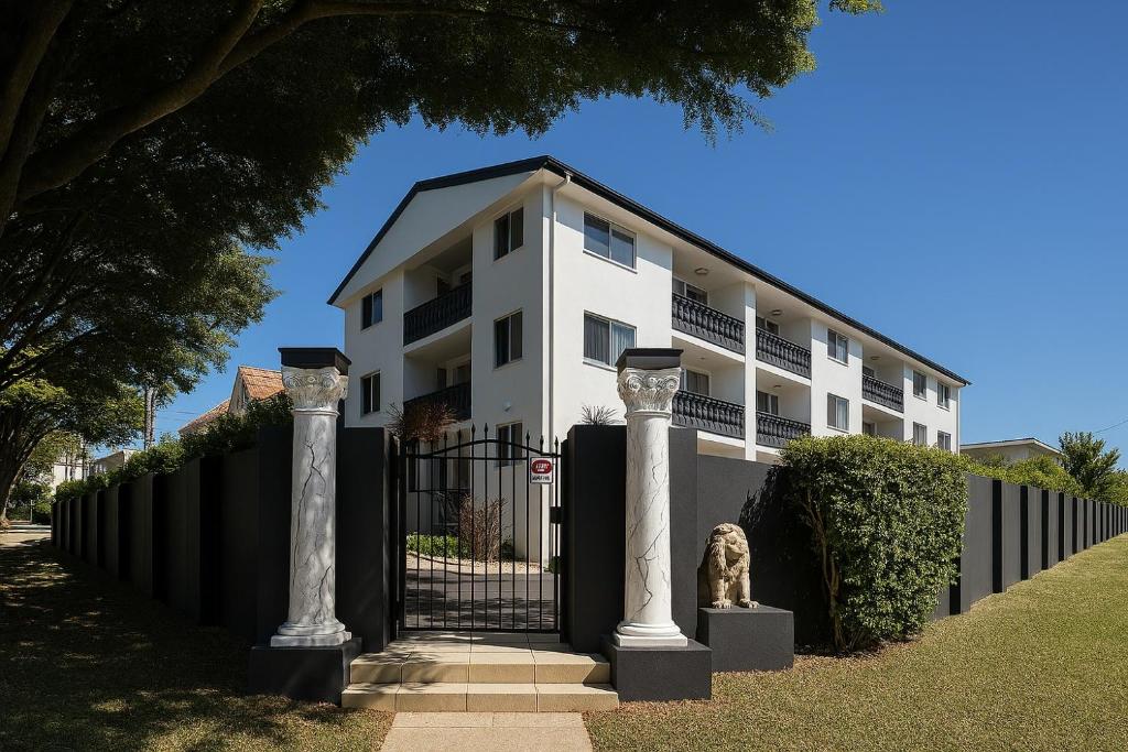 a building with two columns in front of a fence at Redcliffe Villa in Redcliffe