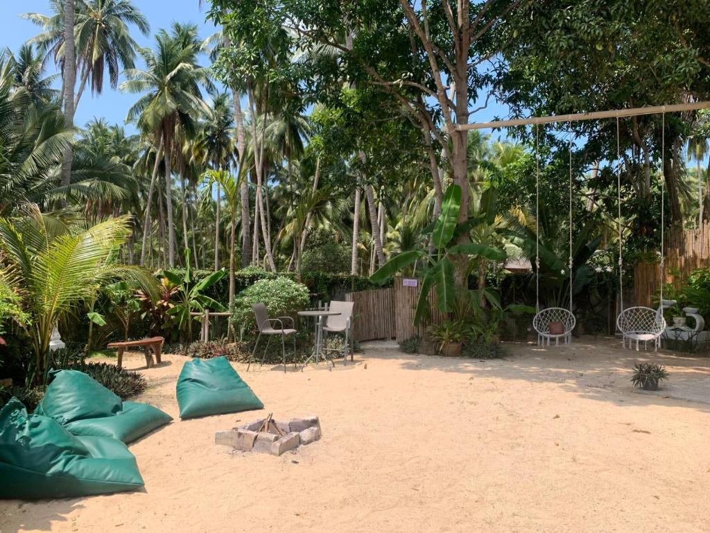 eine Terrasse mit Tisch und Stühlen auf dem Sand in der Unterkunft TRIBE by Aforetime in Taling Ngam Beach