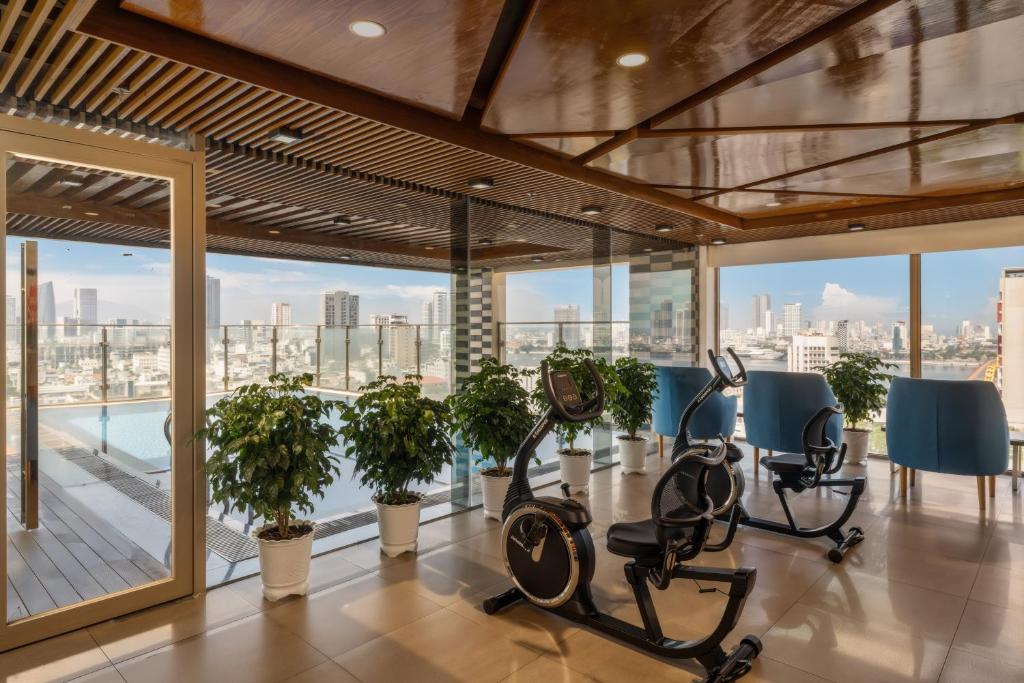 A compact glass-walled fitness room with cardio equipment and city views.