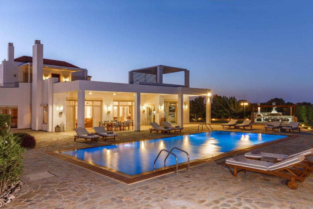 a villa with a swimming pool in front of a house at Belvedere Beachfront Villa in Afantou