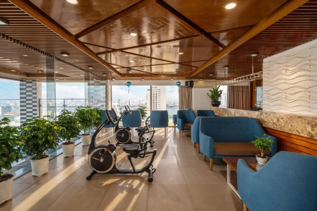 A compact fitness area with exercise bikes, lounge seating and broad city windows.