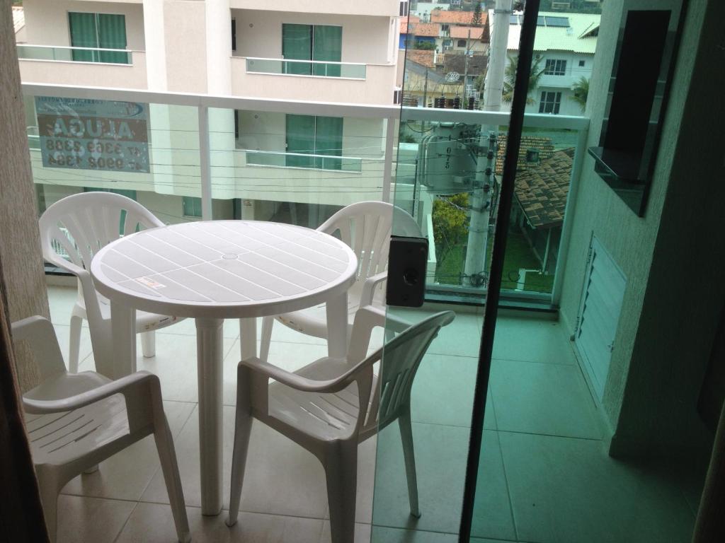 una mesa con 2 sillas y una mesa y sillas blancas en Atalanta I, en Bombinhas