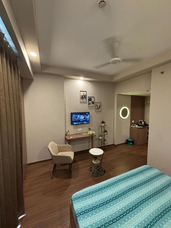 a bedroom with a bed and a chair and a tv at Shagun Stays in Greater Noida