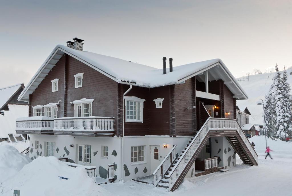 a house covered in snow with a person walking past it at Levin Kalle Apartment in Levi