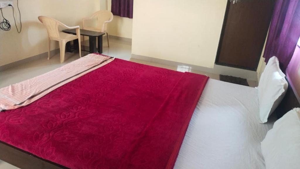 a bedroom with a bed with a red blanket on it at jAYESH PALACE in Loni Kālbhor