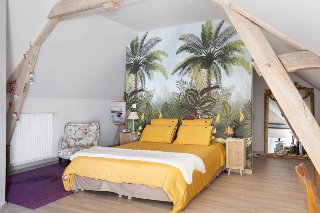 a bedroom with a bed with yellow pillows and palm trees on the wall at Chambre Terracotta in Tavant