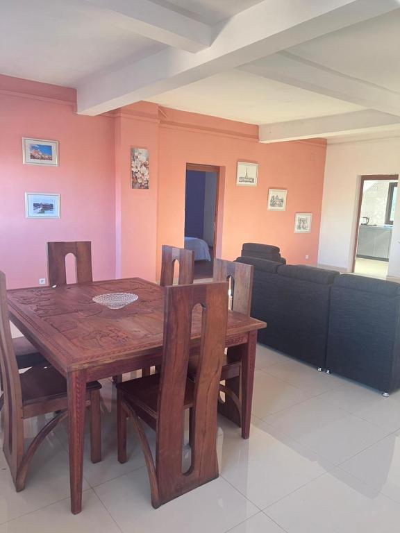 a dining room with a wooden table and a couch at Akany Fitahiantsoa in Ivato