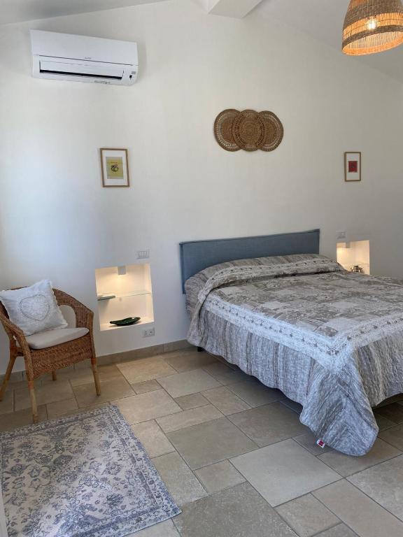 a bedroom with a bed and a chair at La valle dei carrubi in Scicli