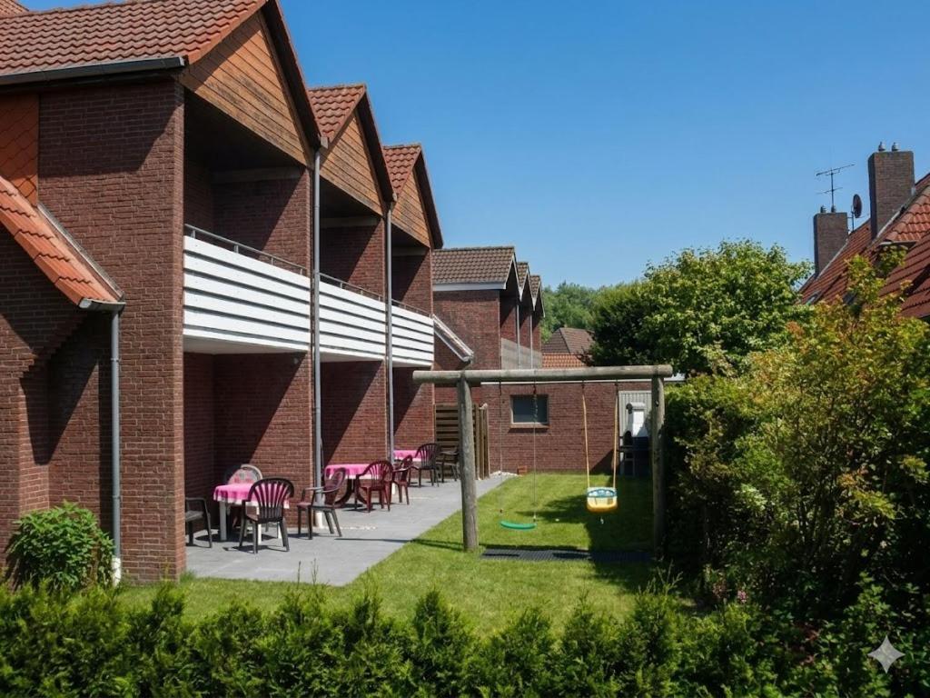 a patio of a brick house with pink tables and chairs at Haus Gertrud in Carolinensiel