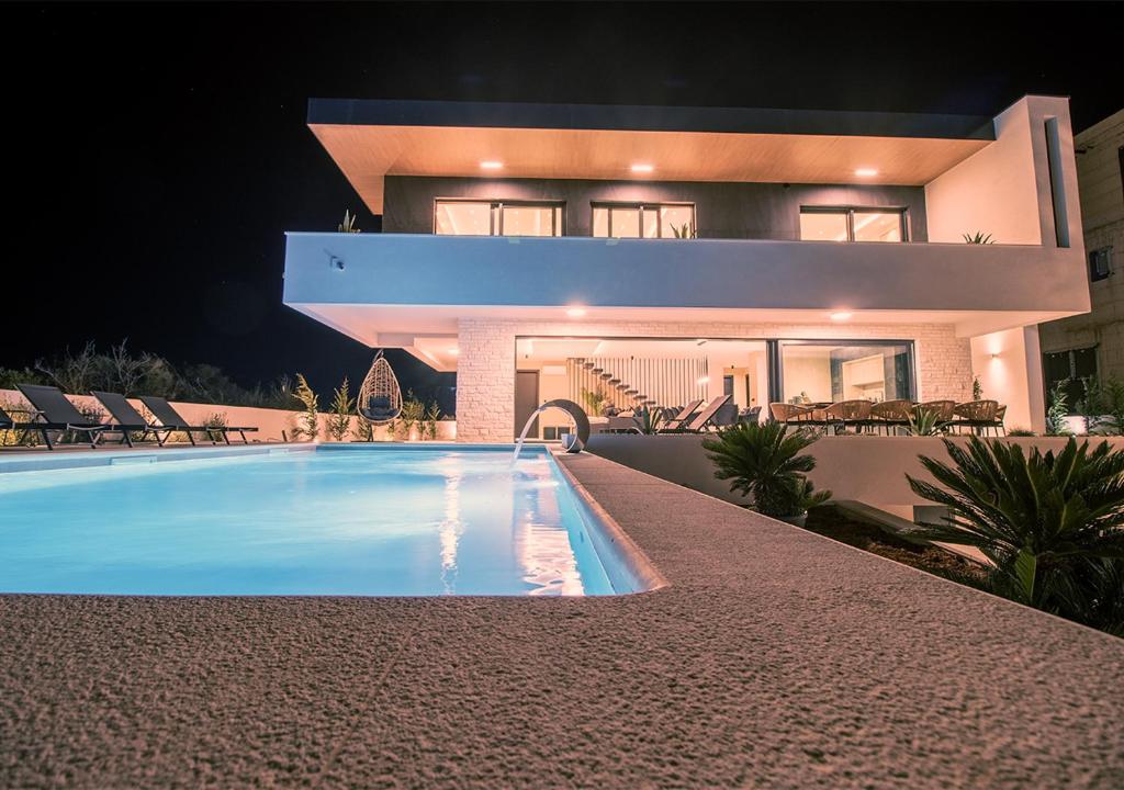 a house with a swimming pool in front of a house at Villa Solis in Novalja