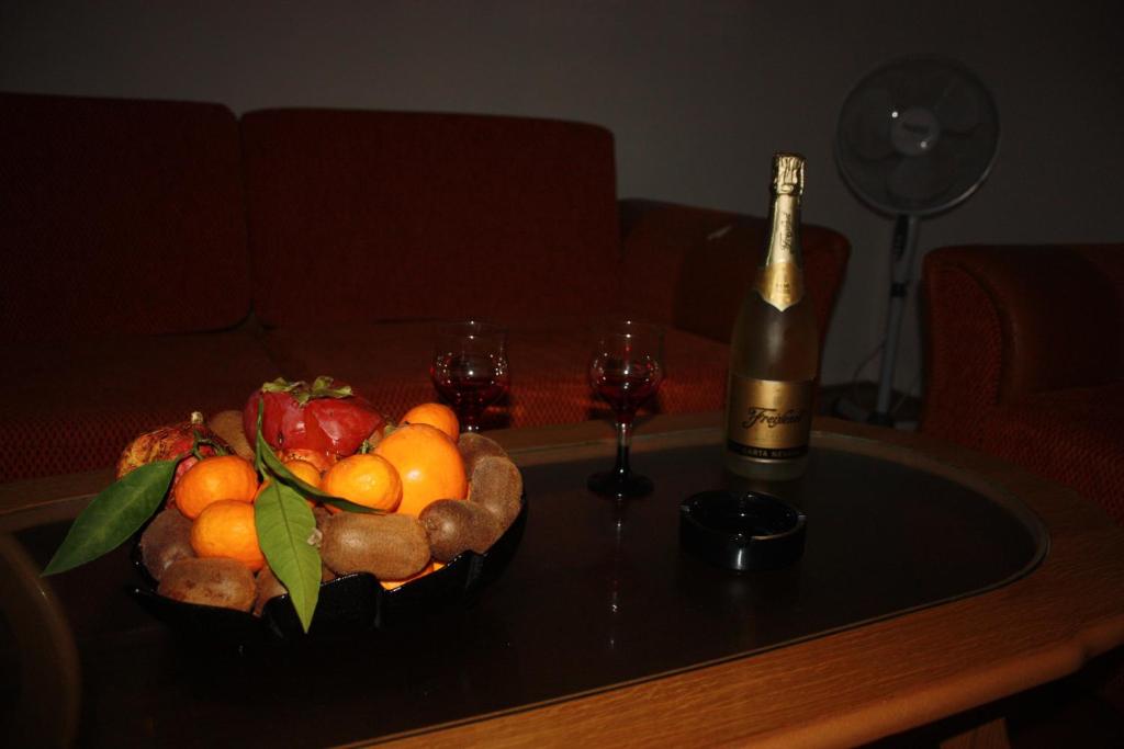 eine Schale Obst auf einem Tisch mit einer Flasche Wein in der Unterkunft Apartmani Sijaric in Dobra Voda