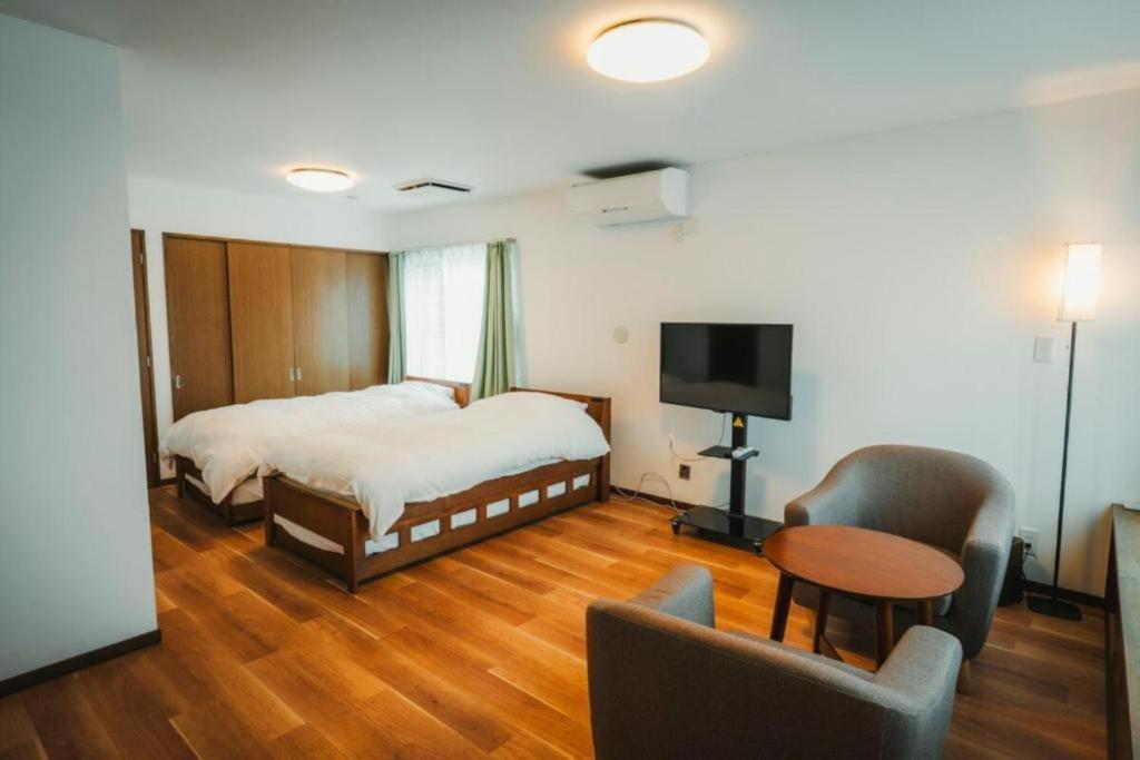 a bedroom with a bed and a table and chairs at 杉 Cedar House in Biei