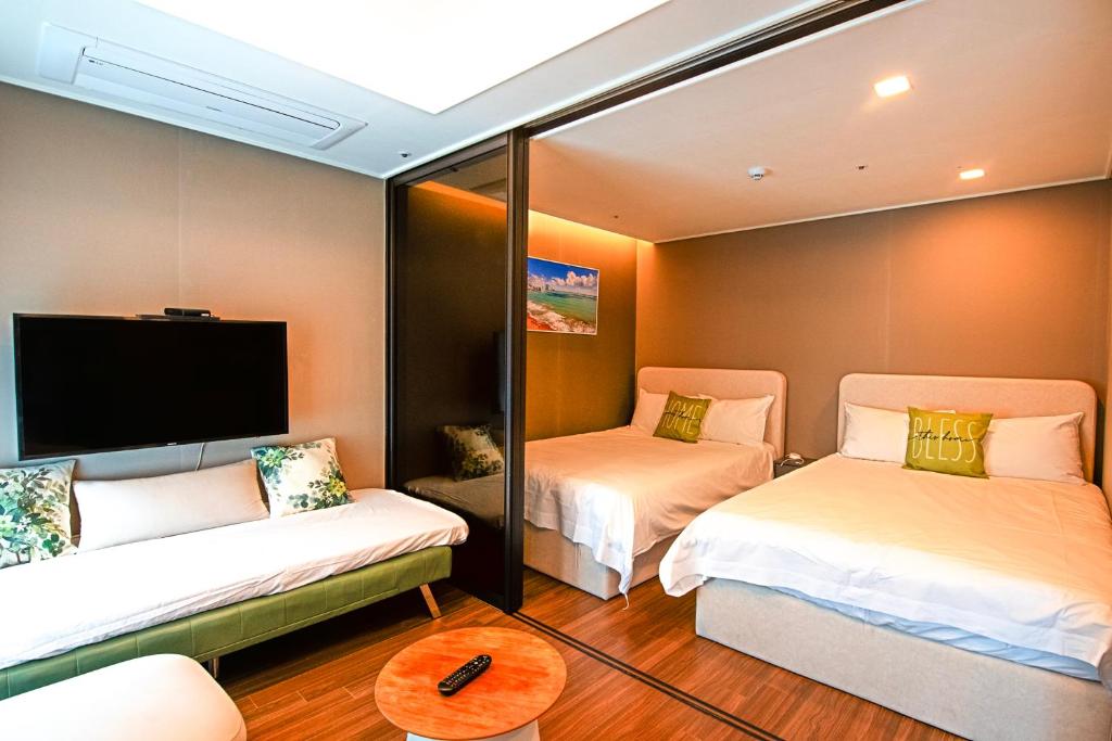 a room with two beds and a flat screen tv at RUNA Stay HAEUNDAE in Busan