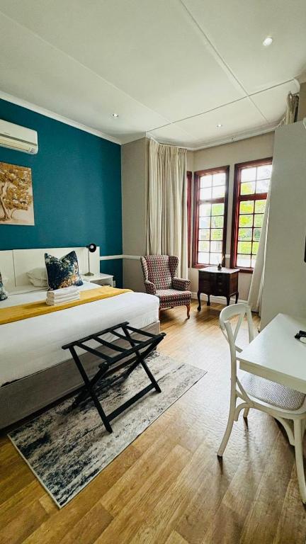 a bedroom with a bed and a couch and a chair at Hidden Villas Guesthouse in East London