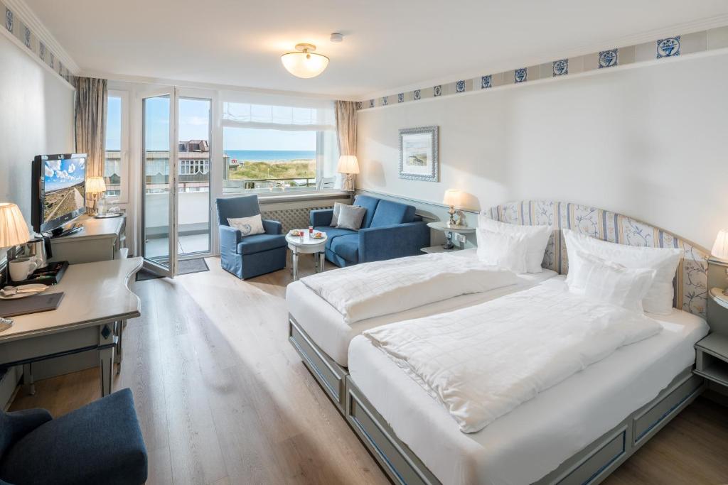 a bedroom with a large bed and a living room at Hotel Wiking Sylt in Westerland