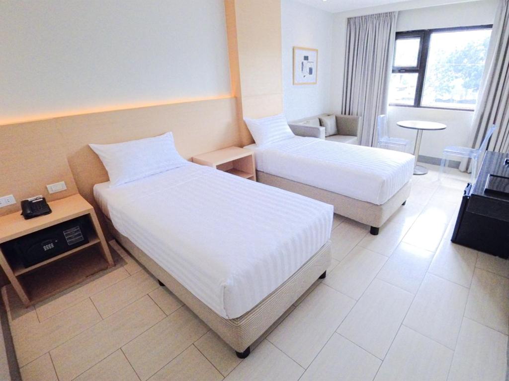 a hotel room with two beds and a table at Red Planet Cavite in Rosario