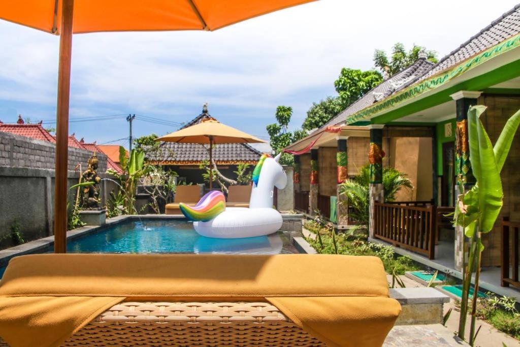 een zwembad met een opblaasbaar speeltje en een parasol bij Reynold Artha Guest House in Nusa Lembongan