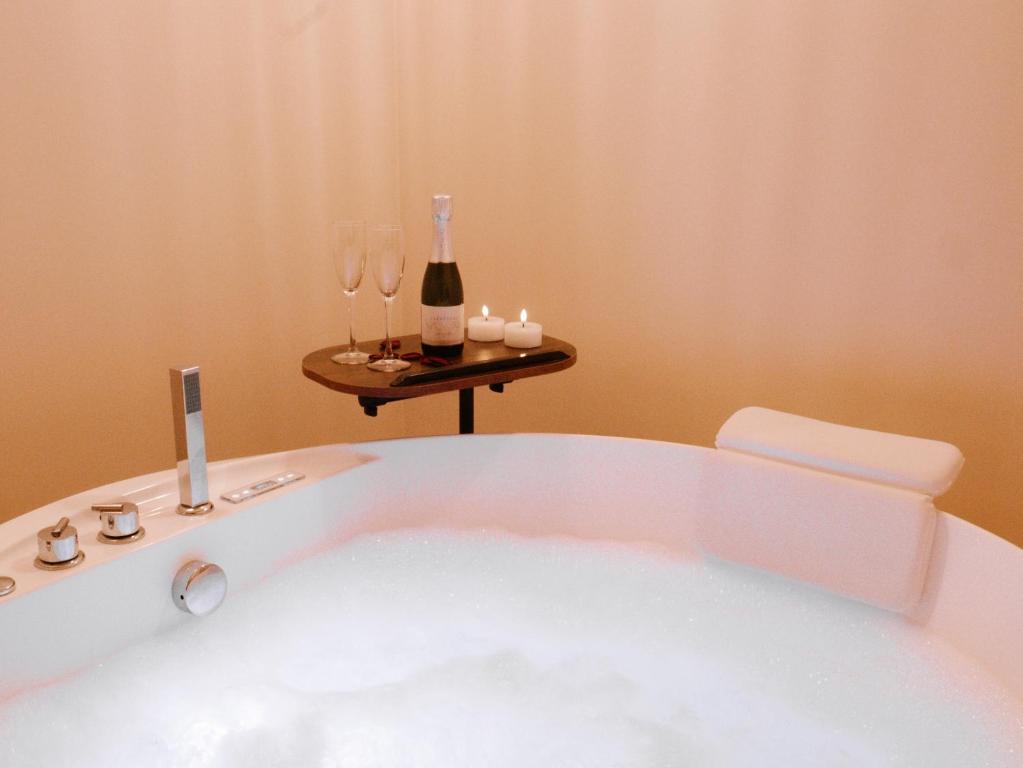 a bath tub with wine glasses and a table with wine bottles at Chalet romantique - Jacuzzi privatif - King size in Montignac-Charente