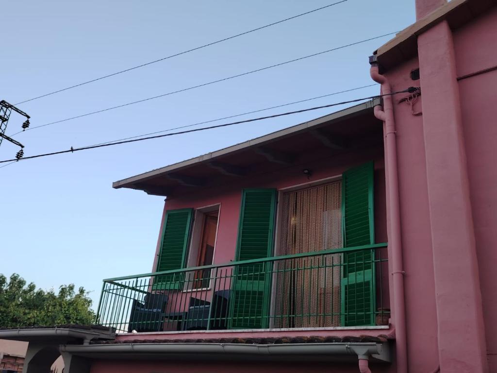 a pink building with a balcony with green shutters at Benvenuti a casa in Certaldo