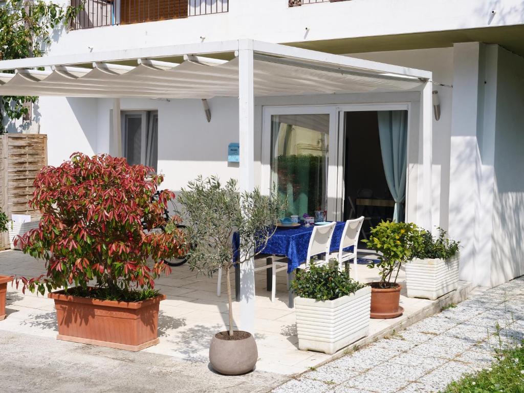a white patio with potted plants and a table at Minerva - bilocale indipendente, posto auto e bici in Grado