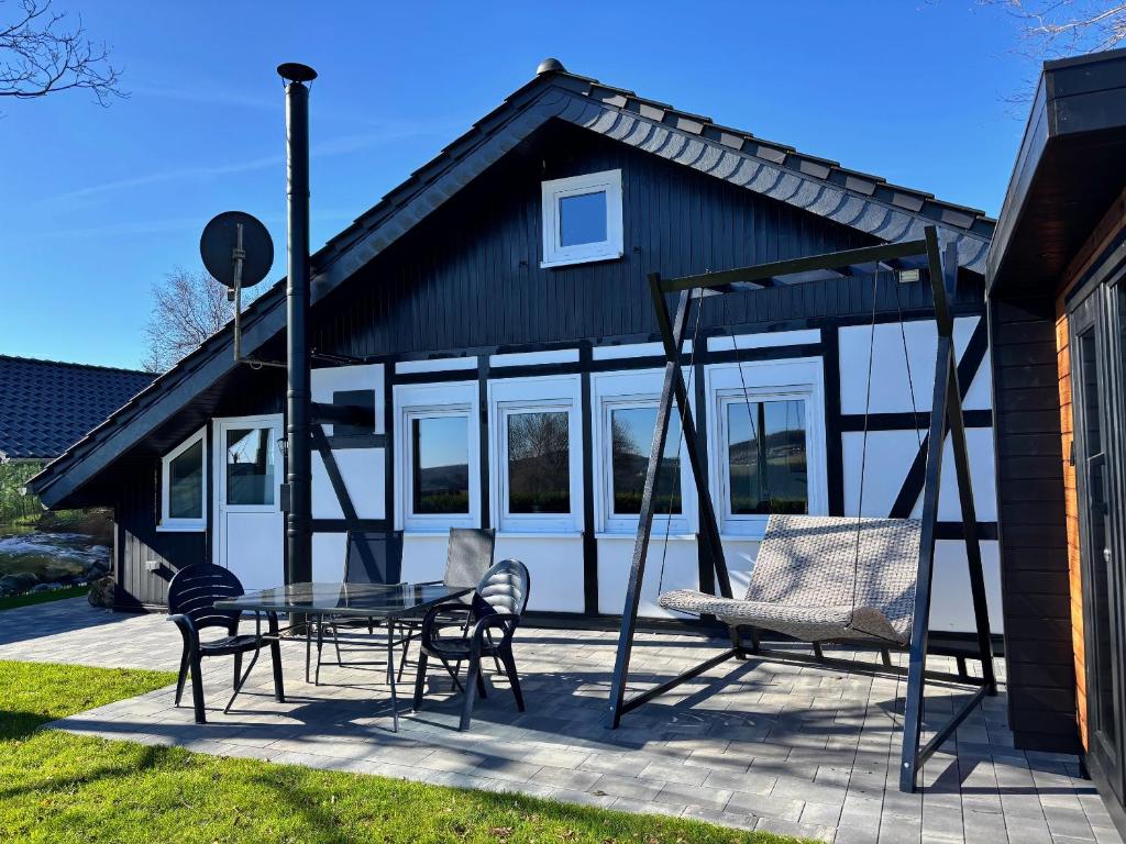 a house with a swing and a table and chairs at Berghütte Astenpanorama in Winterberg