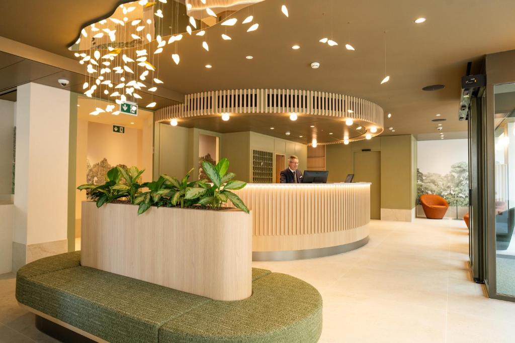 a man is standing at a desk in a lobby at Hôtel le Square in Geneva