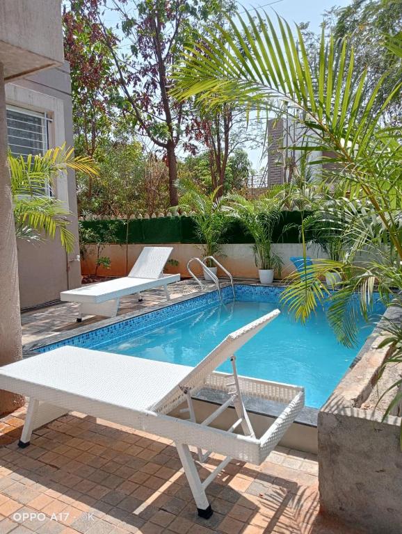 a swimming pool with two lounge chairs next to it at Coco Villa with Private Pool in Karjat