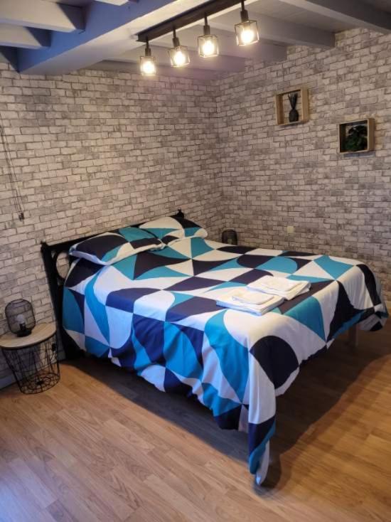 a blue and white bed in a room with a brick wall at le lieu jeanne in Auvers