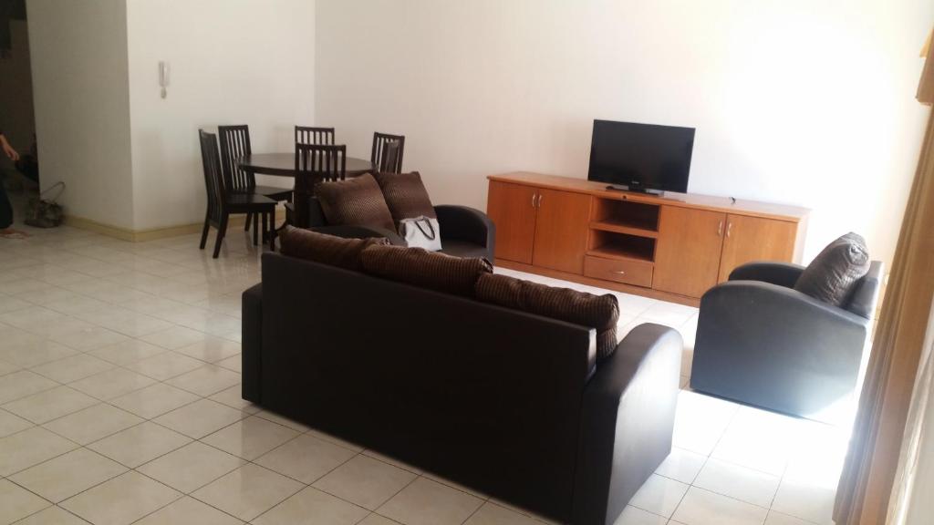 uma sala de estar com sofás, uma televisão e uma mesa em T & H Vacation Condo @Marina Court em Kota Kinabalu