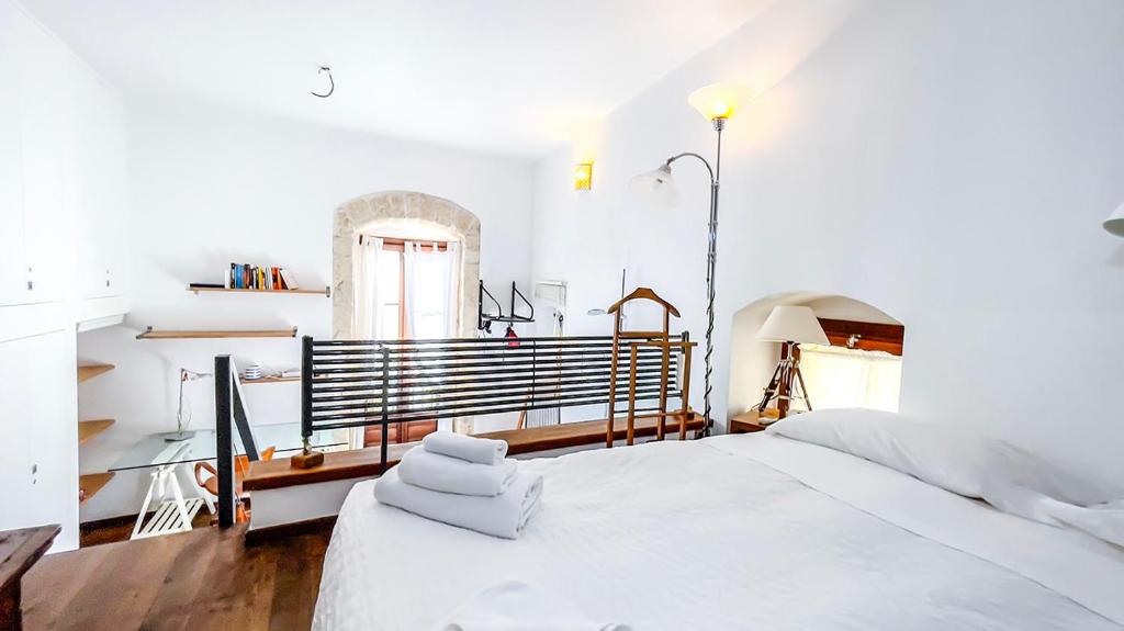 a white bedroom with a large bed and a window at La Baita nel Borgo HOWME in Bari