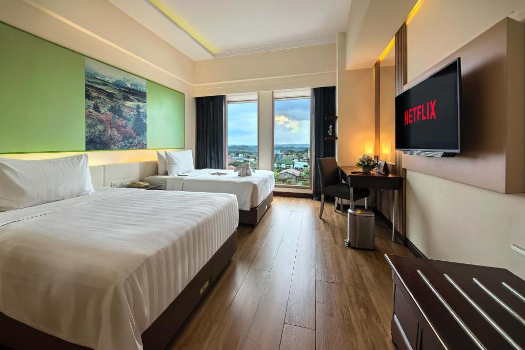a hotel room with two beds and a flat screen tv at Grand Candi Hotel in Semarang