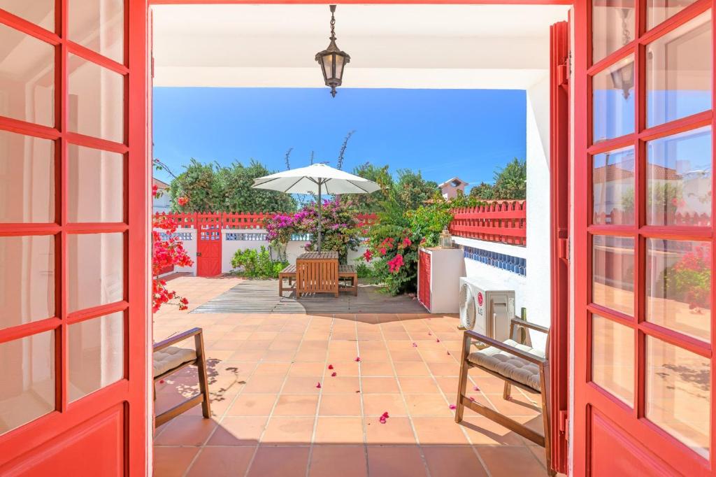 an open door to a patio with an umbrella at Casa Buganvília in Sines