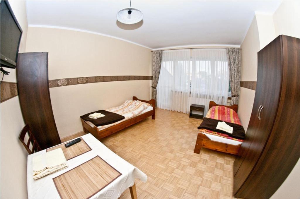 Habitación pequeña con 2 camas y mesa. en Noclegi ZŁOTA RYBKA en Toruń